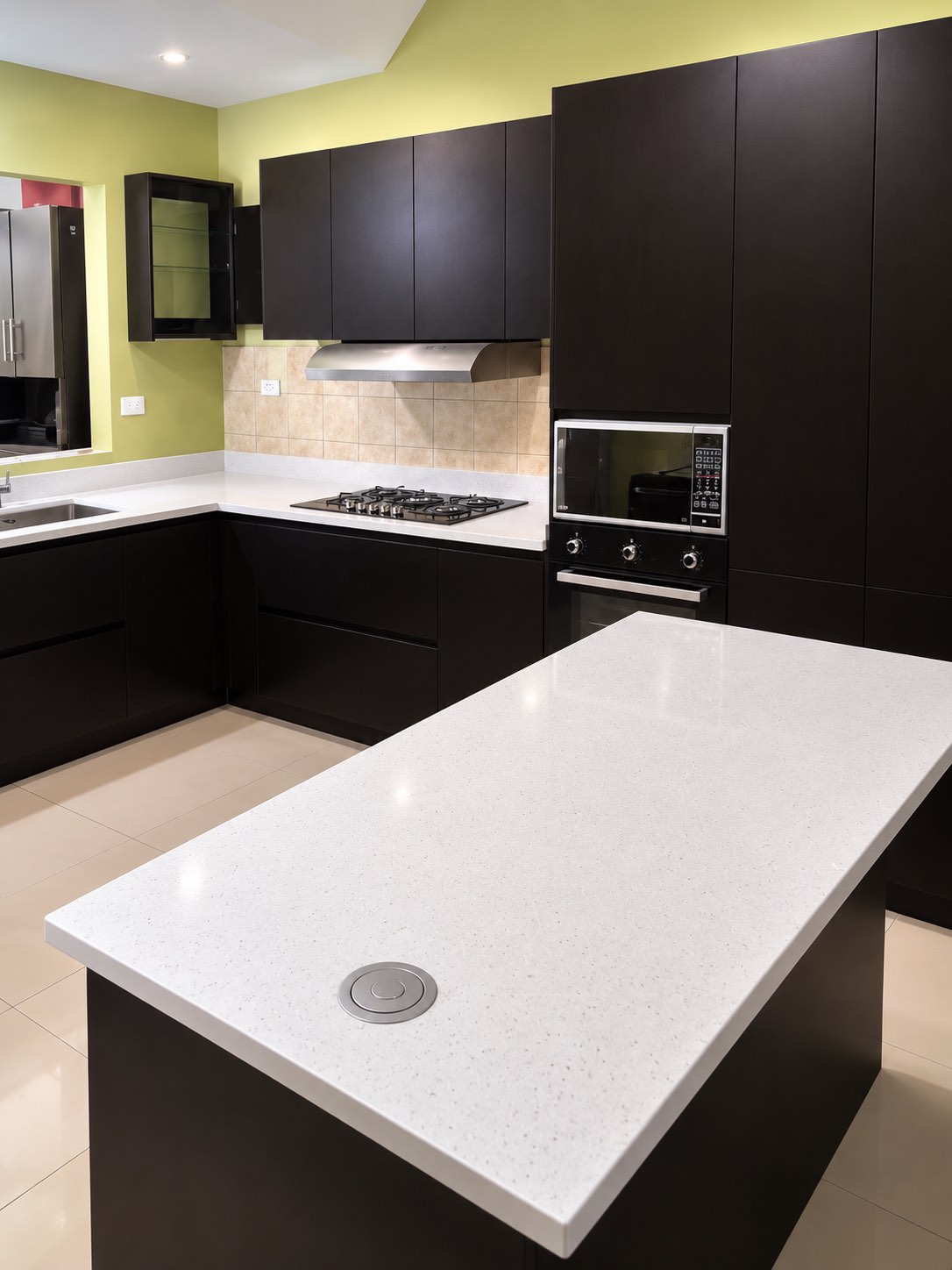 Cocina en gabinetes oscuros con isla de cuarzo blanco